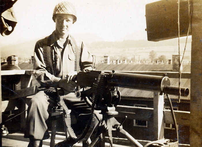 My grandfather on a water cooled 30 caliber machine gun guarding SS soldiers.