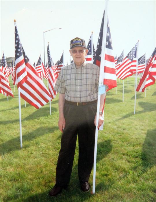 Picture of Walter standing in front of the flag of heroes in Westerville, Ohio.