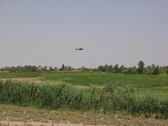 Picture of an AH-64 Apache helicopter flying by the EECP above the farmland that surrounded our base.